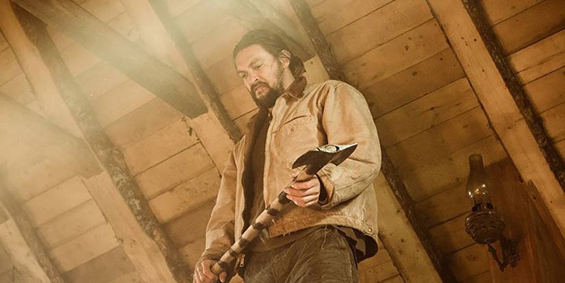 A photo shot from down low of Jason Momoa holding an axe in a scene from Braven.