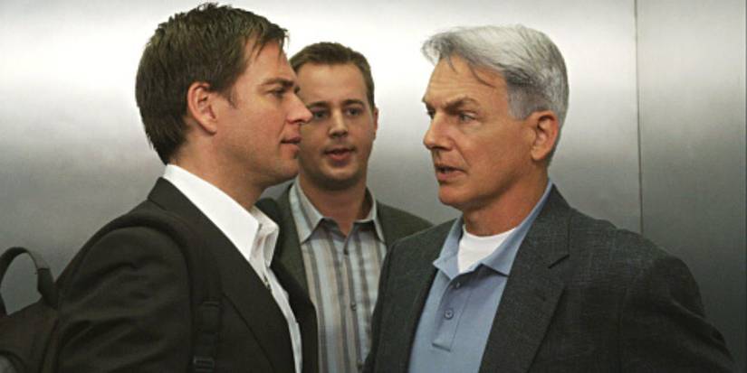 Maikls Veterlijs un Marks Harmons sarunājas liftā, un aiz viņiem stāv Šons Marejs NCIS