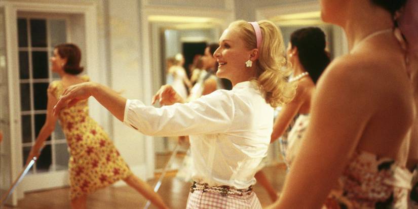 Claire (Glenn Close) smiling as brightly dressed Stepford women clean the room in The Stepford Wives (2004)