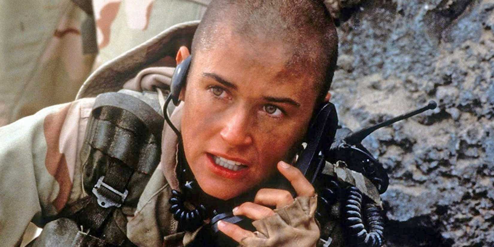 Demi Moore in 'GI Jane' with shaved heads in fatigues speaking into phone on battlefield