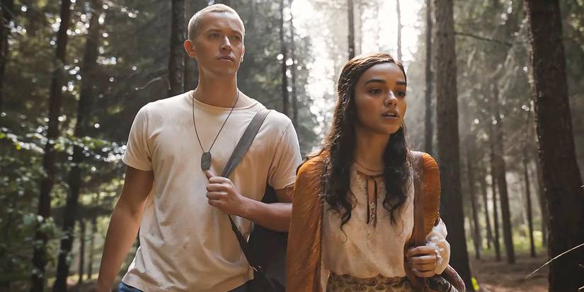 Tom Blyth as Coriolanus Snow and Rachel Zegler as Lucy Gray walking through the woods in The Ballad of Songbirds and Snakes