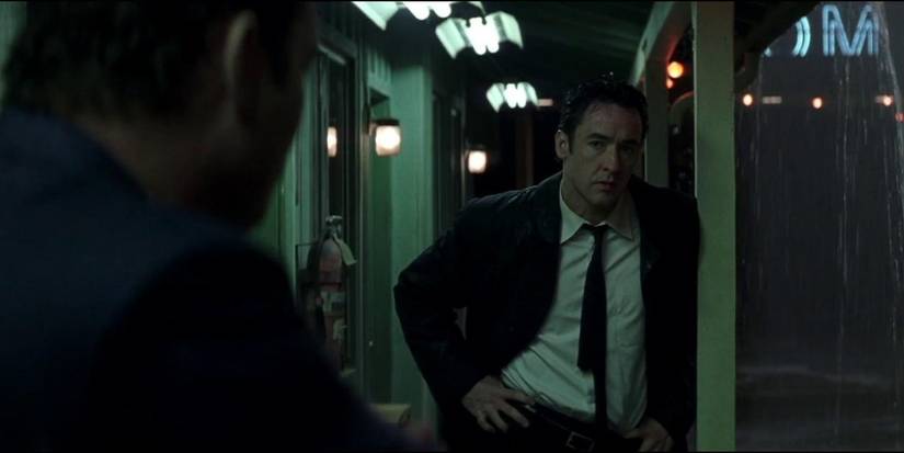 John Cusack stands under the cover of a seedy motel on a rainy night in the 2003 film Identity 
