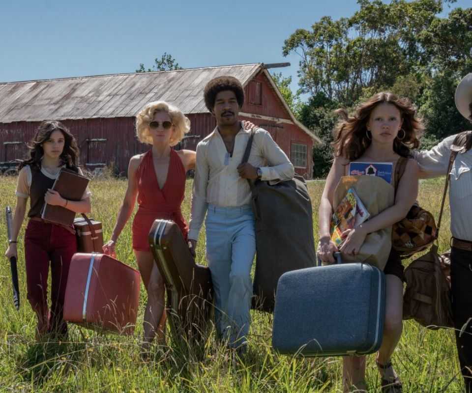 A group of filmmakers walking through a field with their equipment in Ti West's X