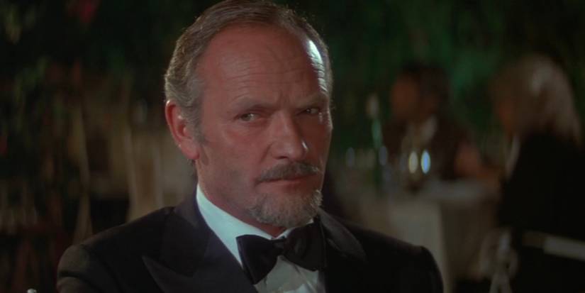 Aristotle Kristatos sits at a restaurant table in a tuxedo in For Your Eyes Only.