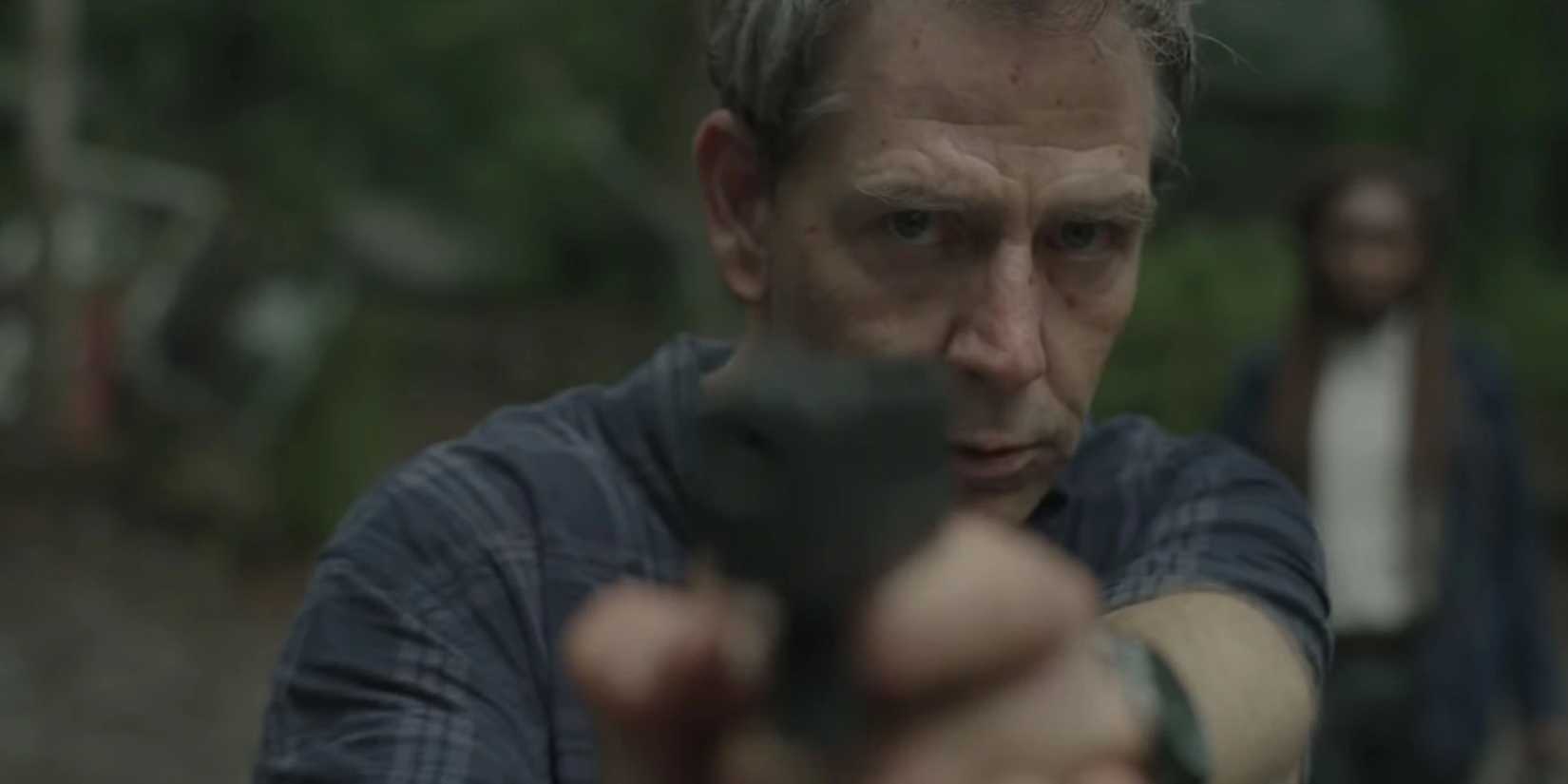 
Ben Mendelsohn as Detective Ralph Anderson pointing a gun at something off camera in The Outsider 