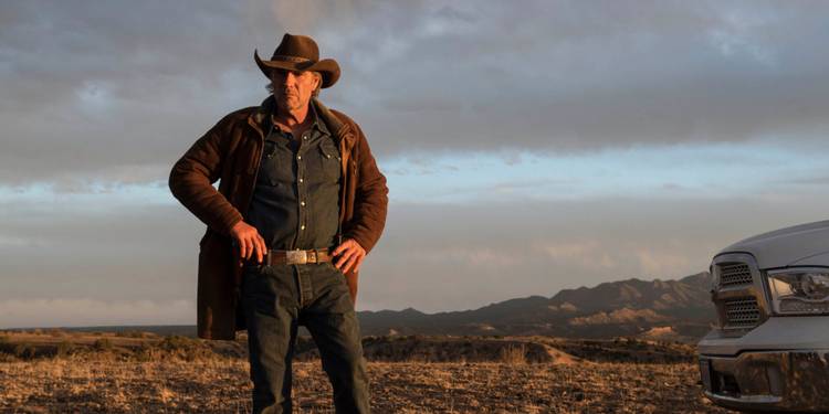 Robert Taylor as Walt Longmire, standing outside at sunset with his hands on his hips in Longmire