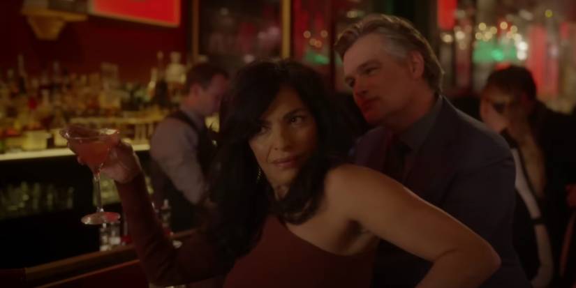 Seema Patel (Sarita Choudhury) holding up a martini glass while a man stands behind her at the bar in And Just Like That Season 2