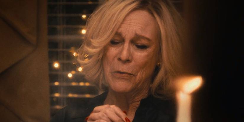 Jamie Lee Curtis as Donna on The Bear, eyes closed and hands clenched together at the dinner table to say grace.