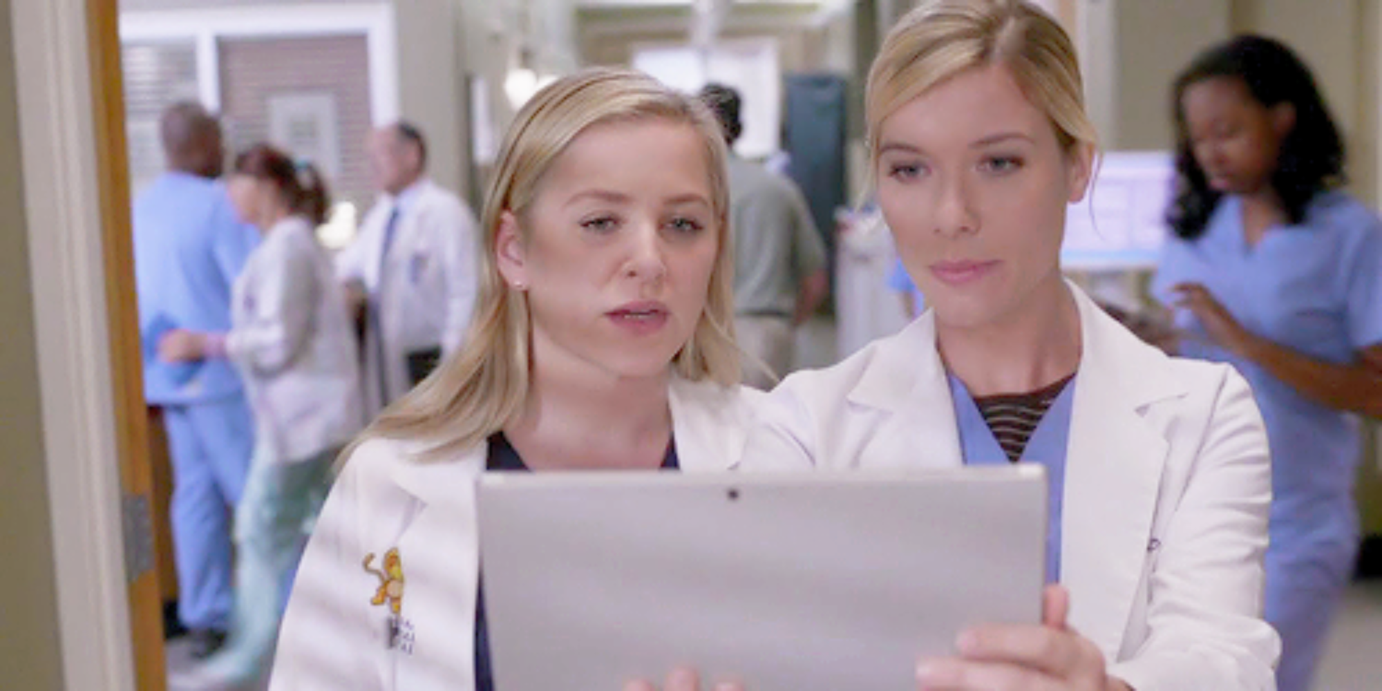 Jessica Capshaw and Tessa Ferrer as Arizona Robbins and Leah Murphy, reading a chart in Grey's Anatomy