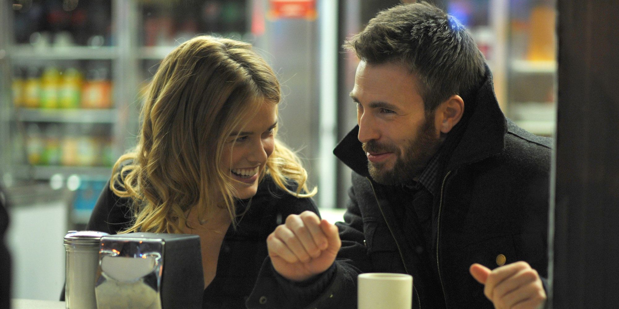 Chris Evans as Nick and Alice Eve as Brooke sit at a diner counter and laugh together in Before We Go.
