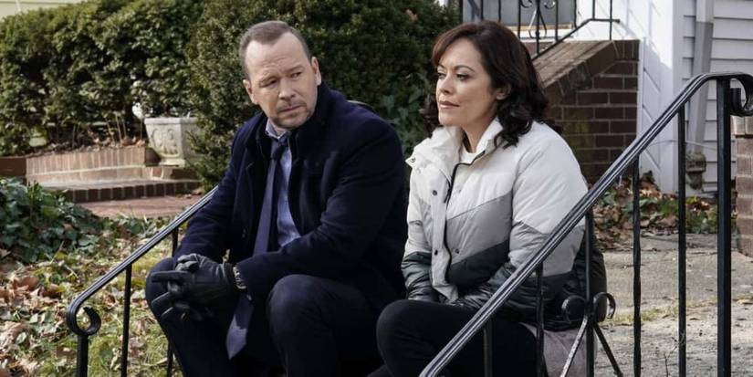 Man and a woman sitting on the stairs outside a house talking.