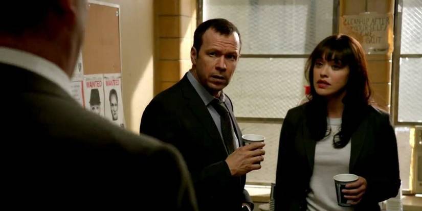 A man and a woman standing together and holding coffee cups.