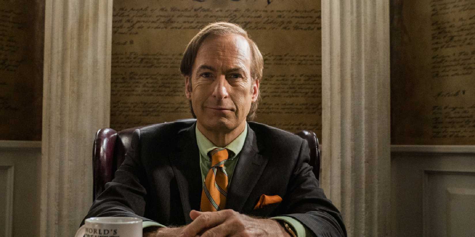 Bob Odenkirk as Saul Goodman in Better Call Saul sitting with his arms in front of him clasped together.