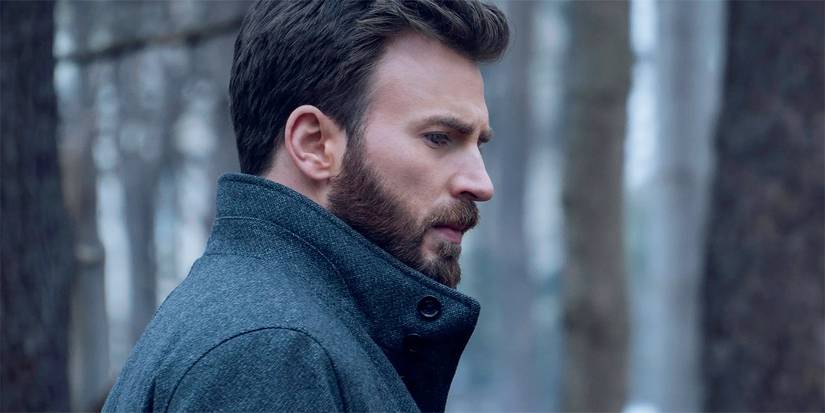 Chris Evans with a serious expression on his face as he stands in the middle of the woods.