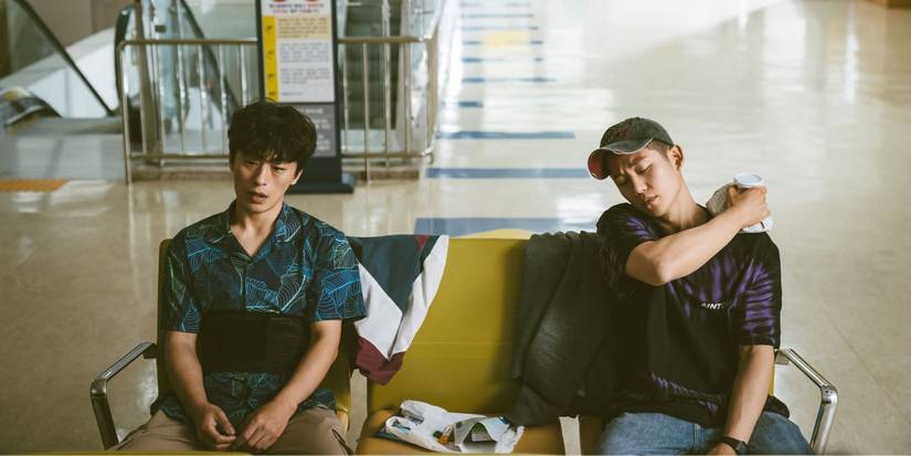 Jung Hae-in and Koo Kyo-hwan as Jun-ho and Ho-yeol sitting injured on a couch in DP.