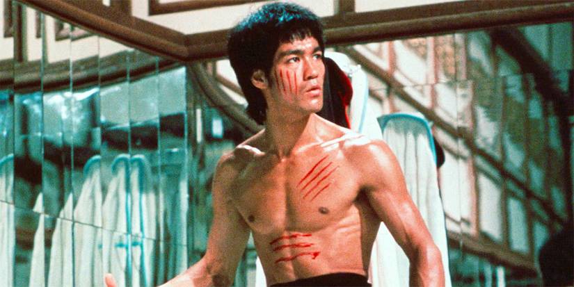 Bruce Lee as Lee, shirtless with scratches on his face and torso, looking to the side in Enter the Dragon.