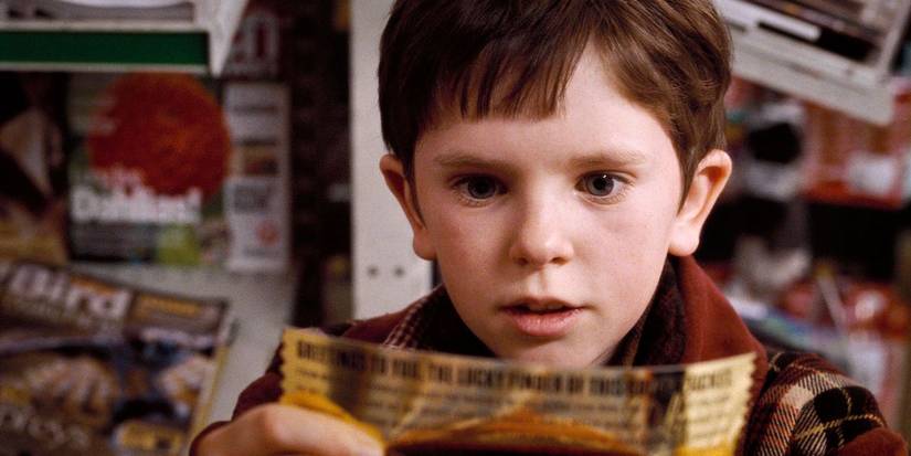 Freddie Highmore as Charlie holding the golden ticket in awe in Charlie and the Chocolate Factory
