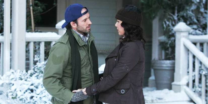 Luke and Lorelai holding hands and looking into each other's eyes in the snow outside Lorelai's house in Gilmore Girls Season 5