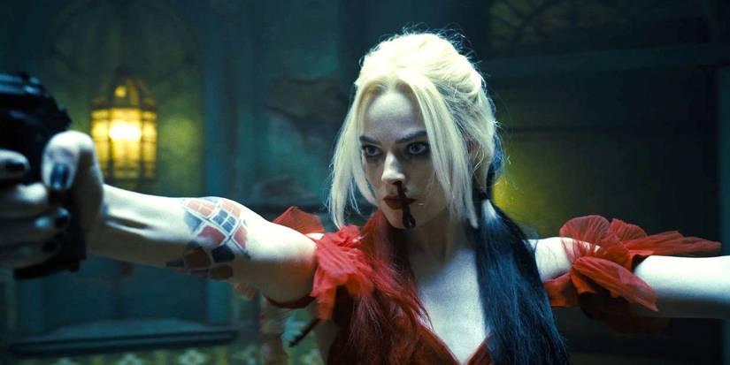Margot Robbie as Harley Quinn, pointing two guns at offscreen threats in The Suicide Squad.