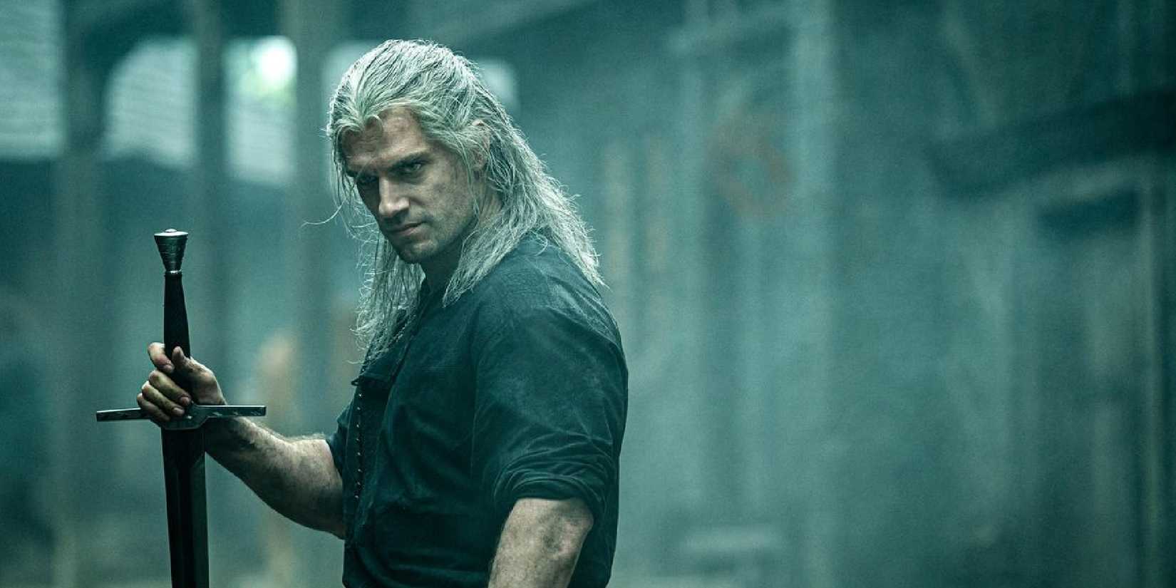 Henry Cavill as Geralt in The Witcher holding a sword against the ground and looking upset.