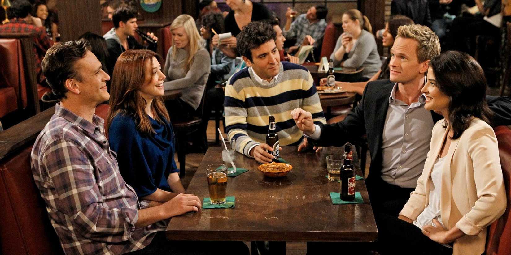 The gang sitting at a table at the pub in How I Met Your Mother 