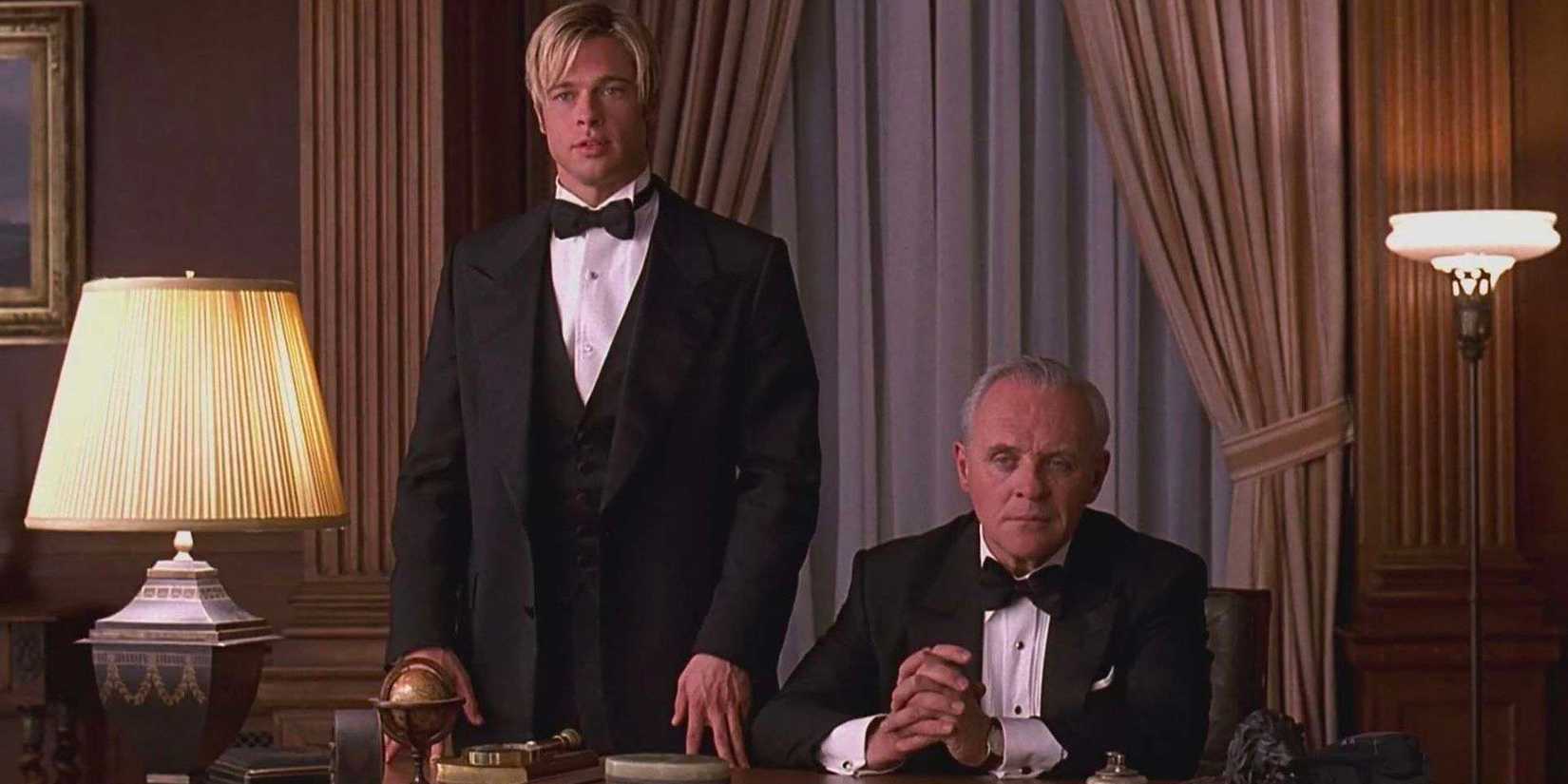 Death (Brad Pitt) stands next to wealthy media mogul Bill Parish (Sir Anthony Hopkins) as he sits behind his desk.