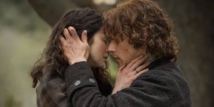 Caitriona Balfe as Claire and Sam Heughan as Jamie about to kiss in the woods in Outlander.