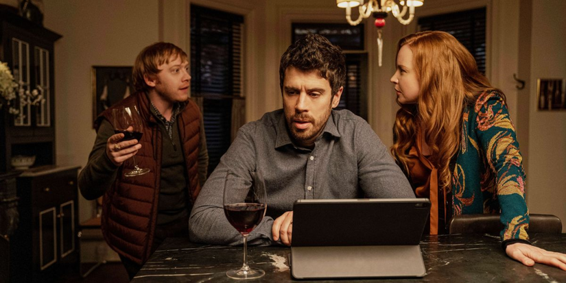 Julian and Dorothy stare at each other behind Sean looking at an iPad in Servant.