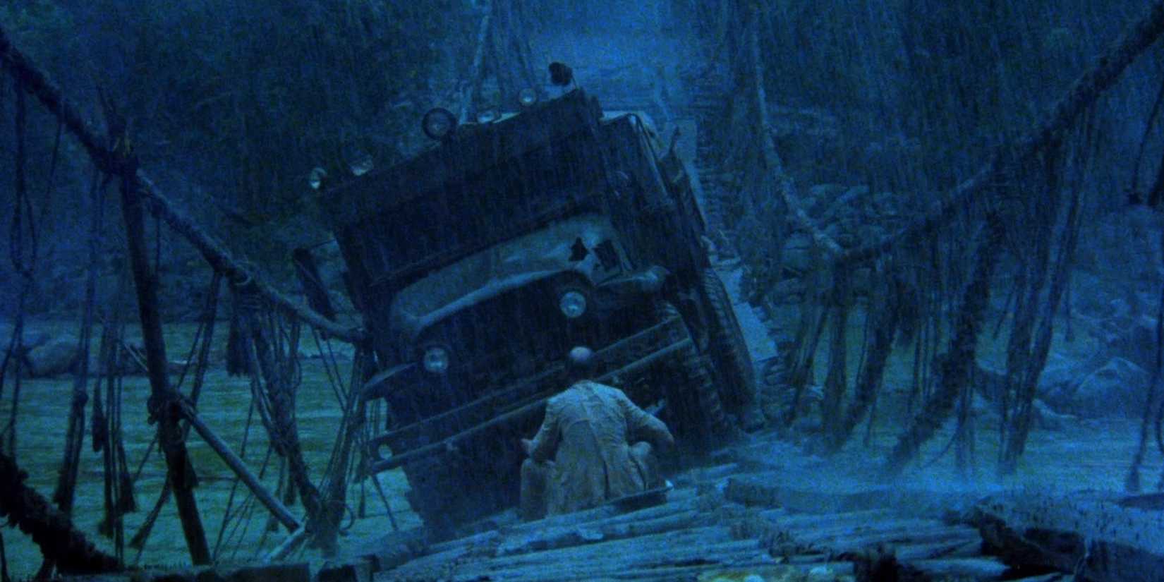 A man crouching in front of a jeep on a broken down bridge in 1977's Sorcerer