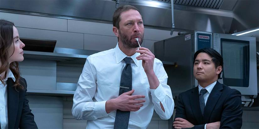 Richie (Ebon Moss-Bachrach) standing in a dress shirt and tie with a spoon in his mouth in 'The Bear.'