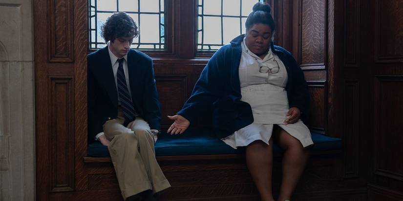 Dominic Sessa and Da'Vine Joy Randolph as Angus and Mary, sitting together while Mary offers Angus her hand in The Holdovers