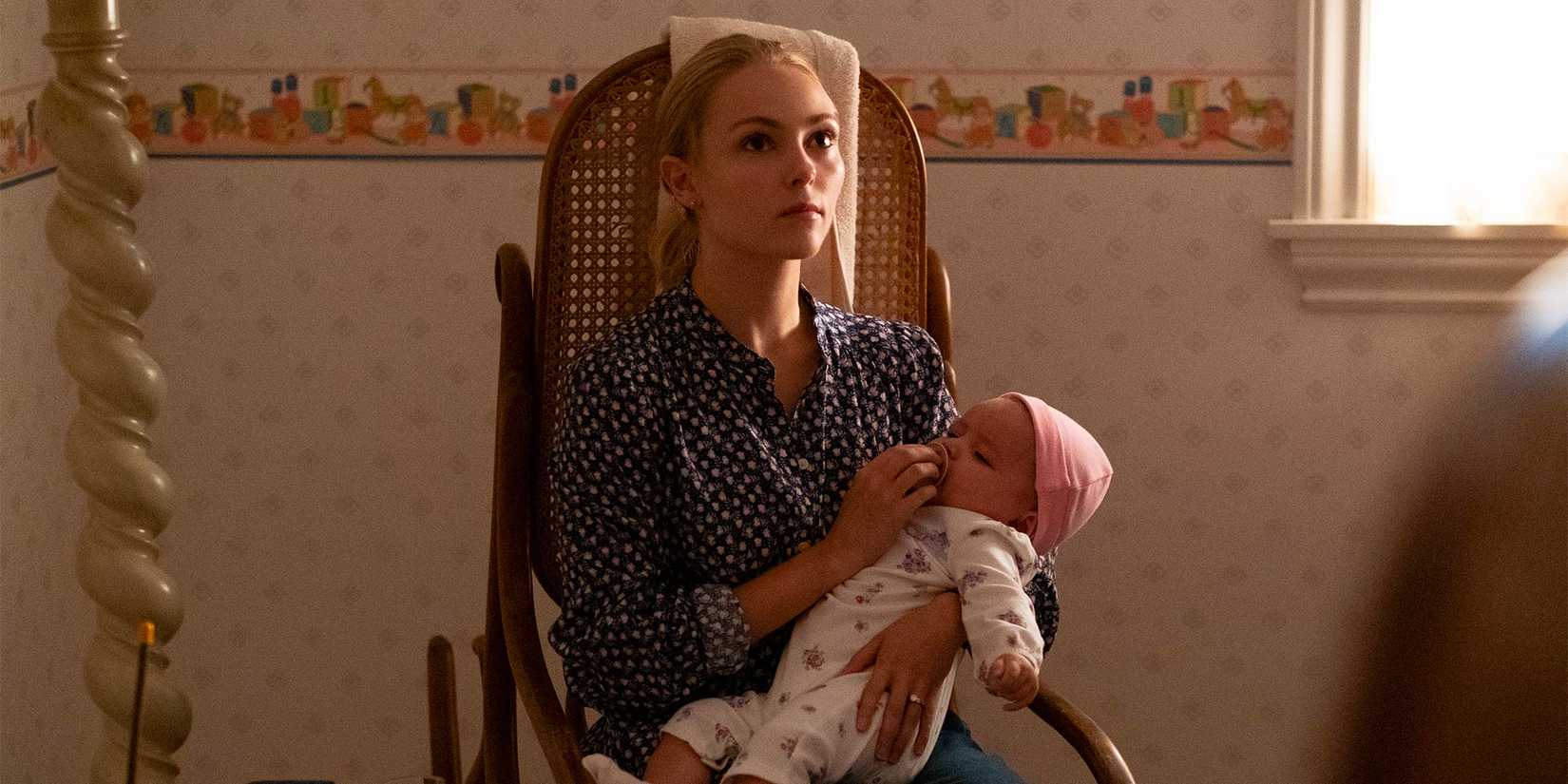 A young Elena Richardson nurses a baby while sitting in a rocking chair.