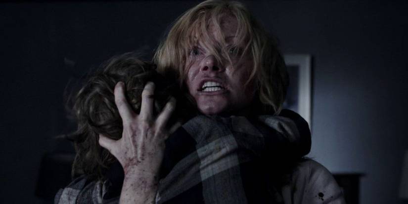 Amelia holding her son and looking ahead with a scared expression in The Babadook.