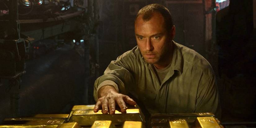A weary man places his hands on a pile of gold bars