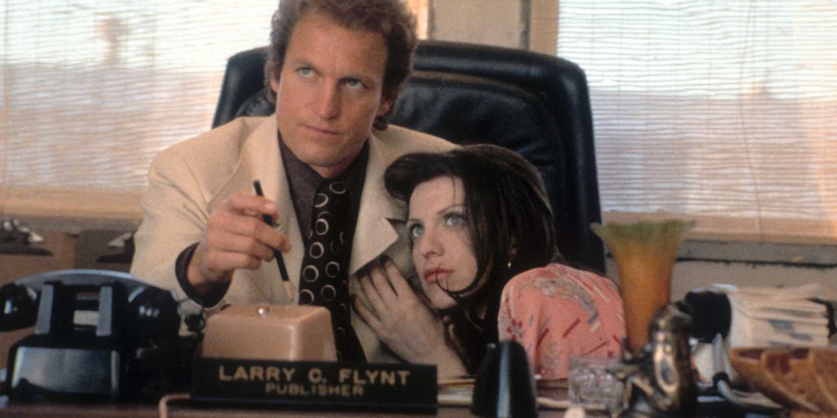 Woody Harrelson and Courtney Love as Larry Flynt and Althea embracing at a desk in The People vs. Larry Flynt