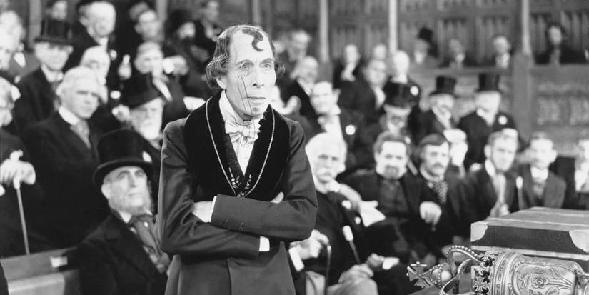 George Arliss as Prime Minister Benjamin Disraeli with his arms crossed in Disraeli
