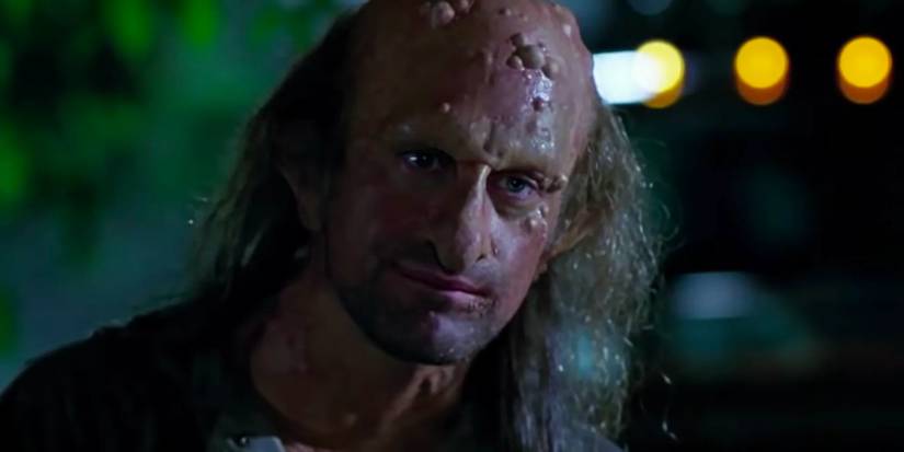 A long-haired man covered in boils and warts stands in the night.