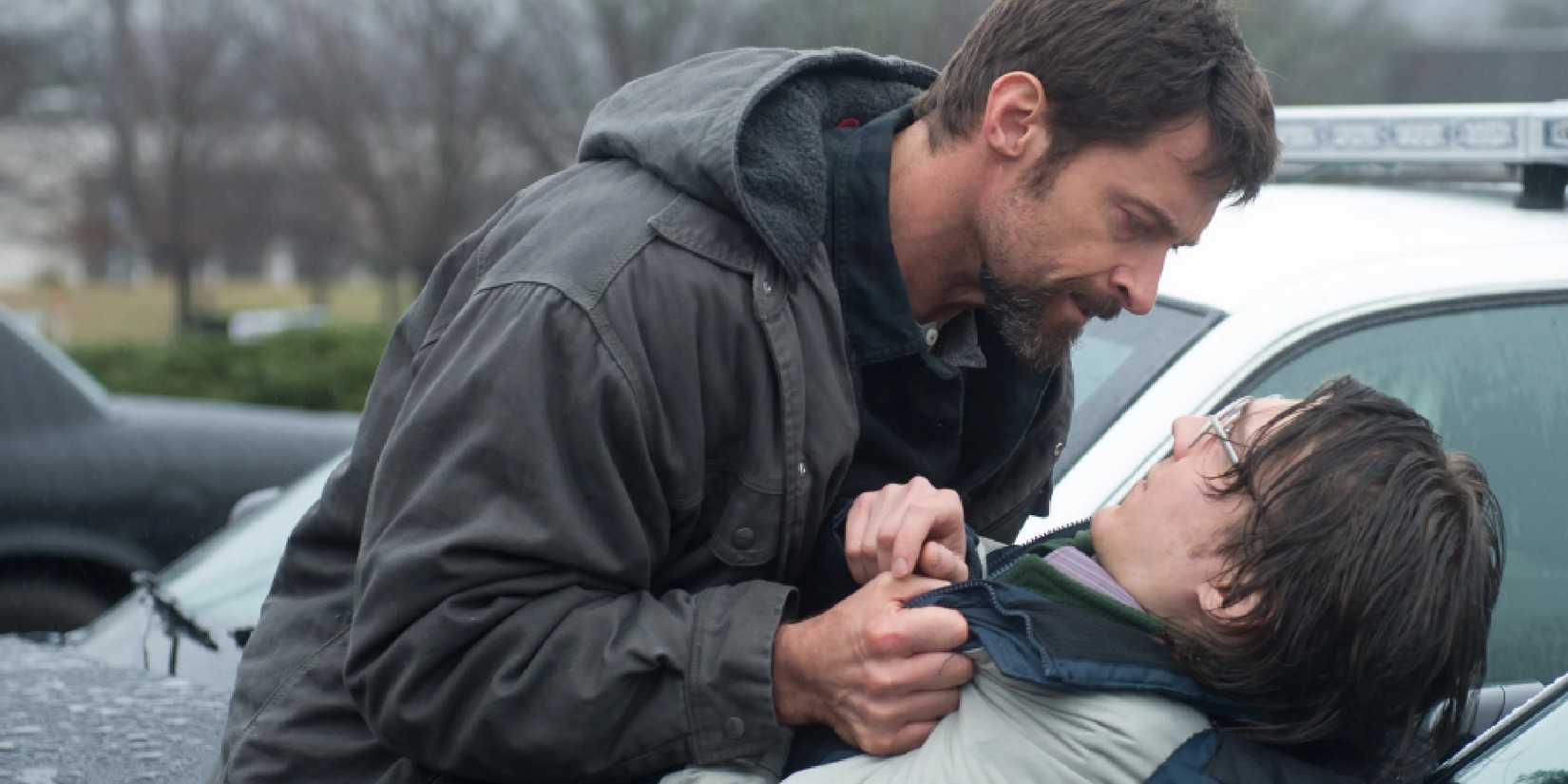Keller holding Alex his the shirt and pressing him against a car hood in Prisoners