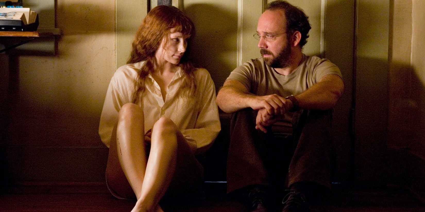 Paul Giamatti dan Bryce DalPaul Giamatti dan Bryce Dallas Howard duduk dan berbicara di sebuah ruangan di Lady in the Water.las Howard duduk dan berbicara di sebuah ruangan