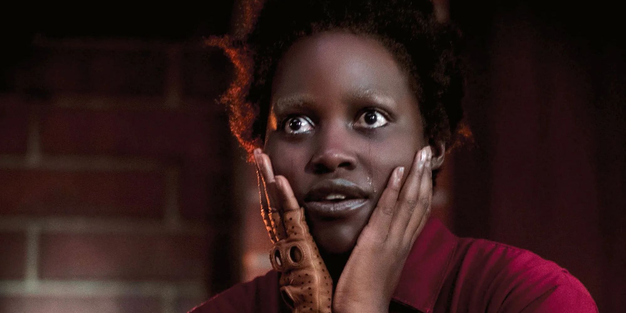 Lupita Nyong'o in Us as Red with her hands up to the sides of her face, and tears streaming down