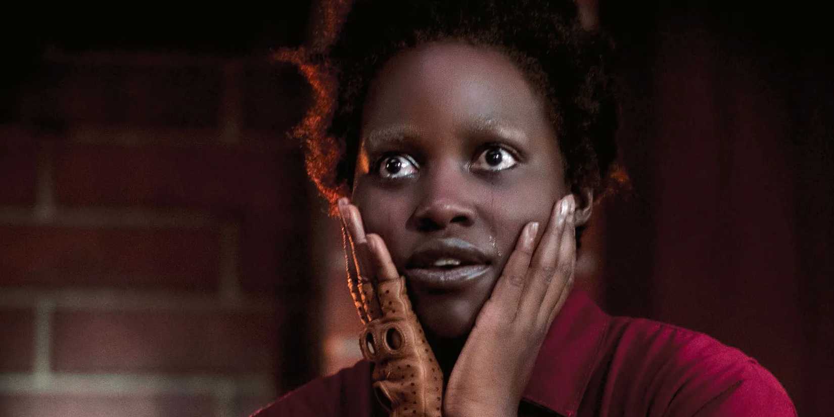 Lupita Nyong'o in Us as Red with her hands up to the sides of her face, and tears streaming down