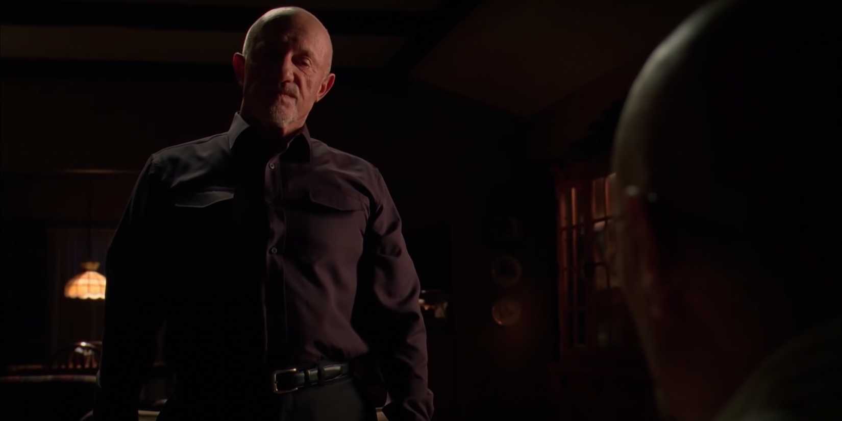Mike sits with Walter in a dimly lit room, telling him about a domestic abuse case he worked when he was a cop.