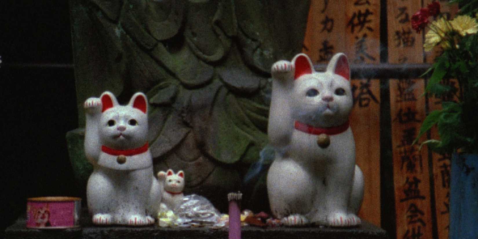 Two waving cat statues in the experimental documentary by Chris Marker, Sans Soleil.