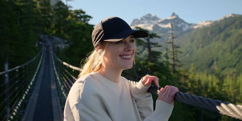 Alexandra Breckenridge as Mel smiling in a baseball cap on a long suspension bridge in Virgin River Season 5