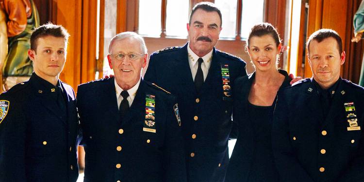 The Blue Bloods Reagan family posing for the camera wearing their uniforms.
