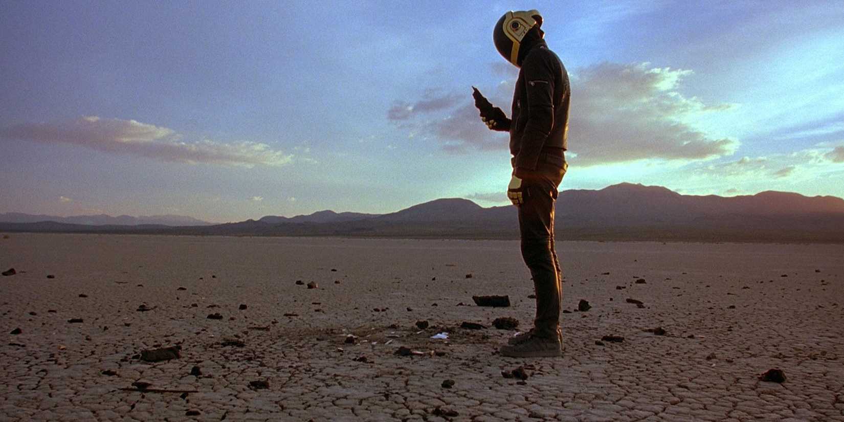 A man in a robotic-looking suit standing in the desert in a scene from Daft Punk's Electroma (2006)