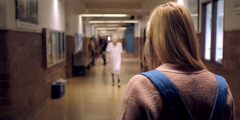Maika Monroe staring at the Entity, now an old woman in a nightgown, in It Follows