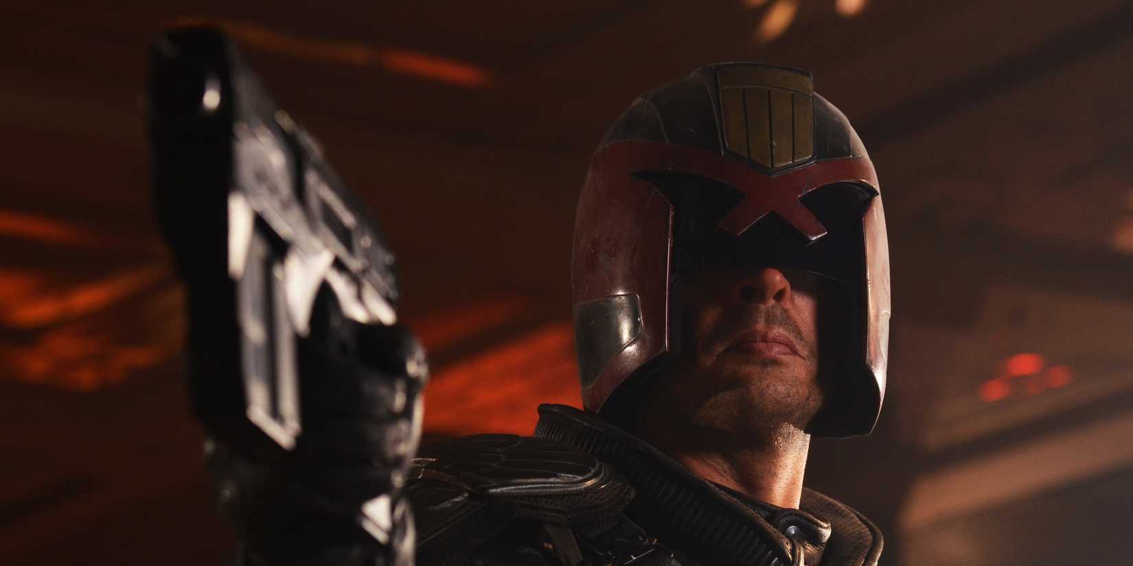 Karl Urban with a helmet on in Dredd, pointing a gun at someone.
