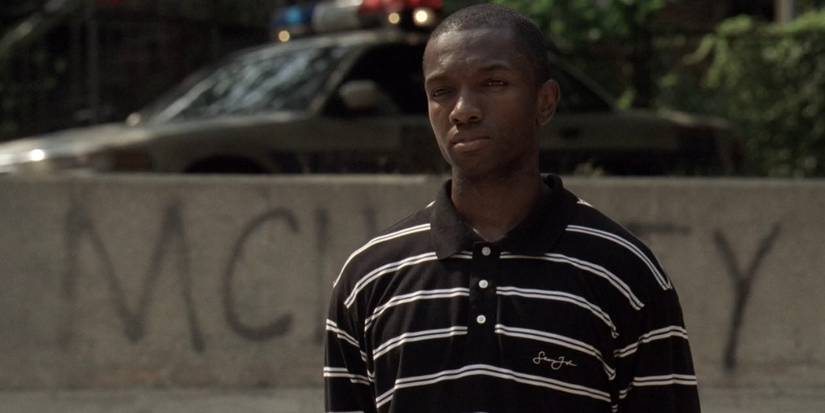 Drug kingpin Marlo Stanfield (Jamie Hector) stands in front of a graffiti wall with a cop car in the background.