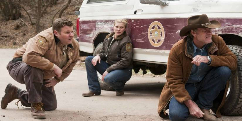 Victoria 'Vic' Moretti (Katee Sackhoff ), Ferg (Adam Bartley), e Walt Longmire (Robert Taylor) agachados atrás de um carro de polícia em Longmire